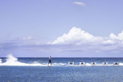 Side view of man amidst infinity pool and sea against sky