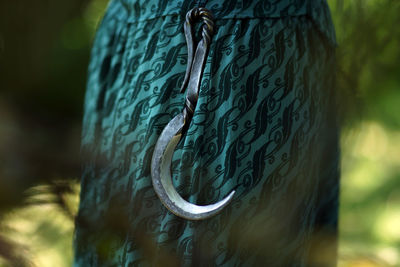 Old hand forged iron sickle on waist of green dress