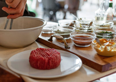 Close-up of professional chef making steak tartare on trolley with spices and ingredients