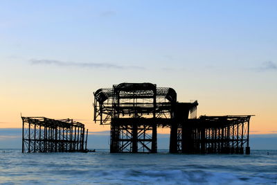 Silhouette built structure on beach against clear sky