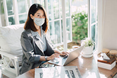 Portrait of businesswoman wearing mask sitting at cafe