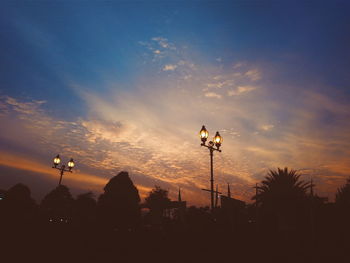 Low angle view of illuminated street light against sky