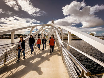 People walking on railway bridge against sky