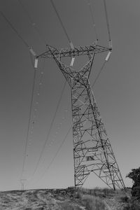 Low angle view of electricity pylon against clear sky
