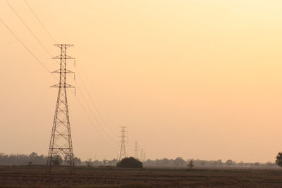 Silhouette electricity pylon on field against romantic sky at sunset