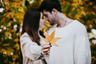 Low angle view of woman holding maple leaf during autumn