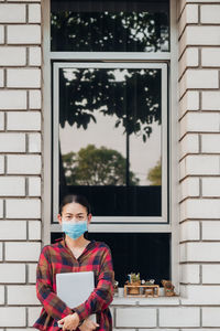 Portrait of man standing against window of building