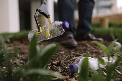 Mature man picking up empty plastic bottles with waste picker from park