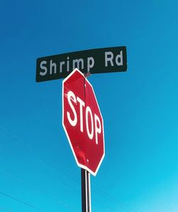 Low angle view of road sign against blue sky