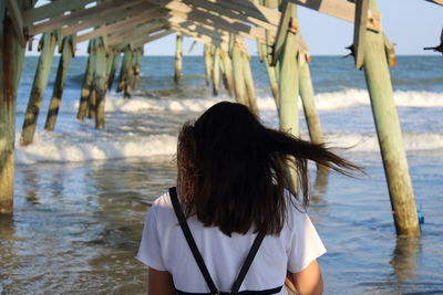 Rear view of woman standing at beach