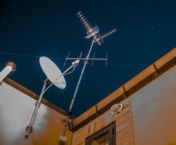 Low angle view of telephone pole against sky at night