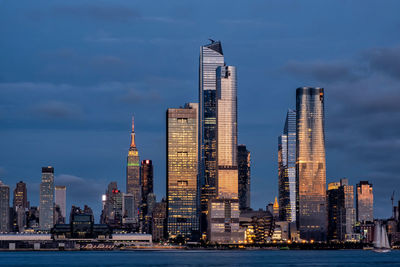 Sea by modern buildings against sky in city