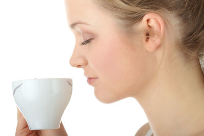 Close-up portrait of a beautiful young woman drinking water against white background