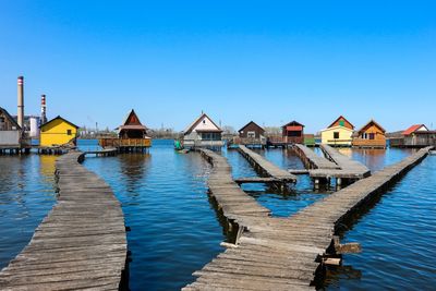 Pier amidst buildings against clear blue sky