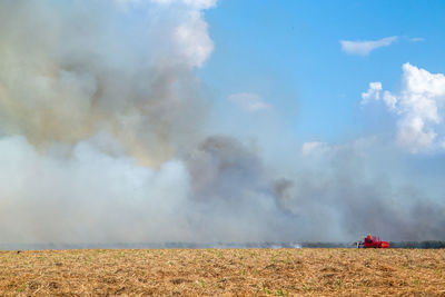 Smoke emitting from field against sky