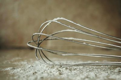 Close-up of wire whisk with flour on table