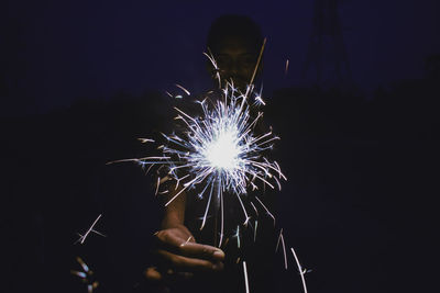 Close-up of human hand holding illuminated sparkler at night