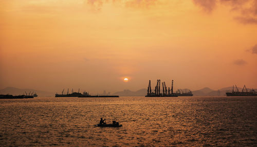 Silhouette sailboats in sea against sky during sunset