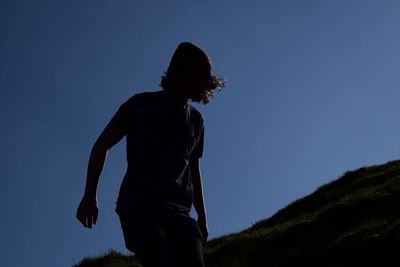 Low angle view of man against clear blue sky