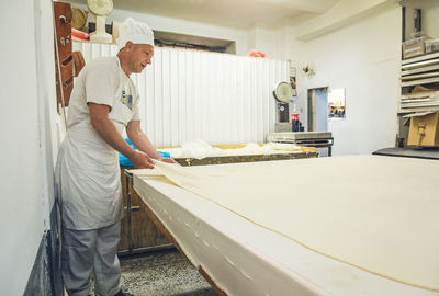 Baker stretching dough across a table at a bakery in belgrade, serbia