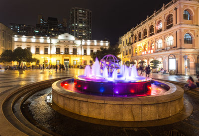 Illuminated fountain in city at night