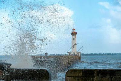 Lighthouse by sea against sky