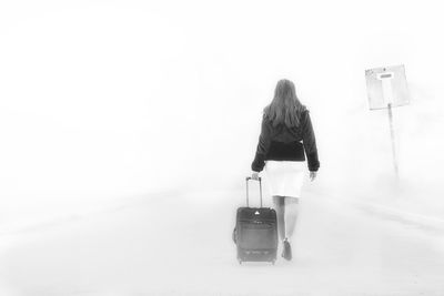 Rear view of woman standing on airport runway against sky