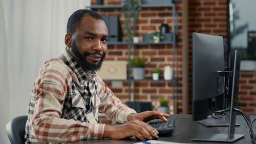 Portrait of young man using laptop while sitting on table