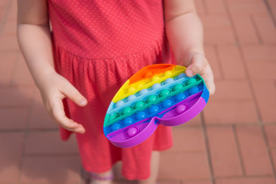 Midsection of woman holding multi colored umbrella