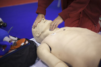 Midsection of man practicing on cpr dummy at hospital