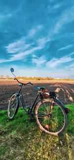 Bicycle parked on field against sky