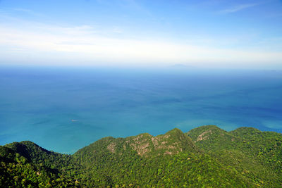 Scenic view of sea and mountains against blue sky