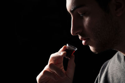 Close-up portrait of young man against black background