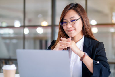 Female business person looking at laptop in office