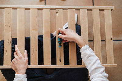 Low section of woman holding screw driver with furniture