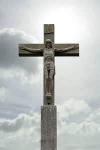 Low angle view of jesus christ on cross against cloudy sky