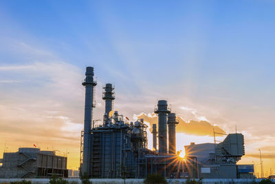 Smoke stacks against sky during sunset