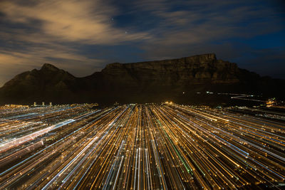 Light trails on mountain against sky at night