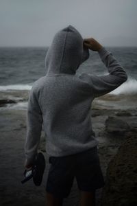 Rear view of man standing at beach against sky