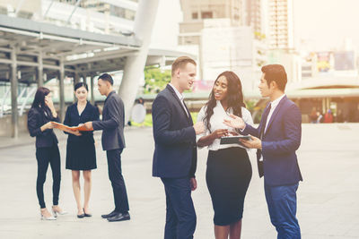 Business colleagues discussing while standing on footpath in city