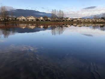 Scenic view of lake by buildings against sky