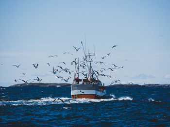 Fishing vessel sailing on sea against clear sky
