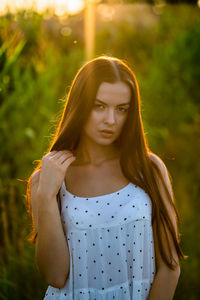 Portrait of young woman standing against plants