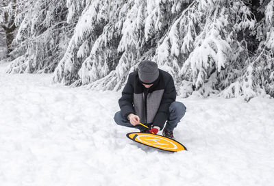 A young man sets up a platform for a drone in a winter forest.