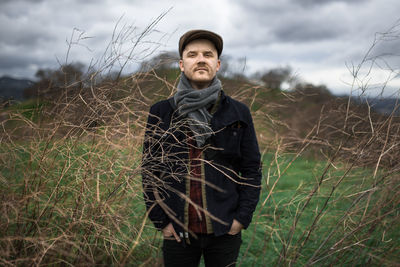 Portrait of man standing in tall branches with stormy skies