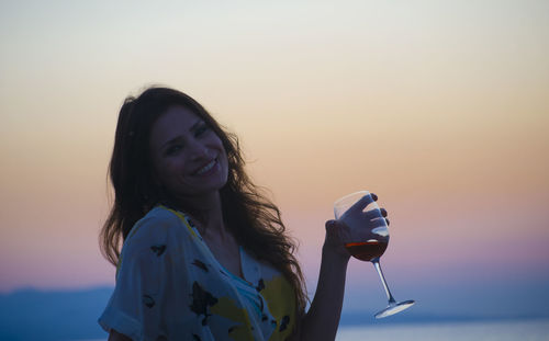 Young woman drinking red wine at sunset