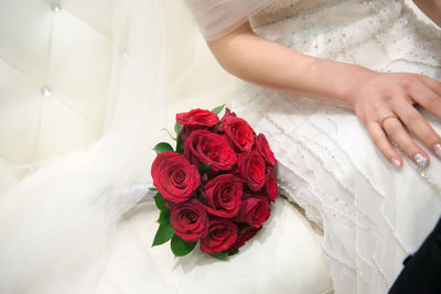 Midsection of bride with red roses bouquet