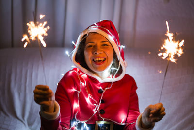 Portrait of happy girl holding sparkler at night