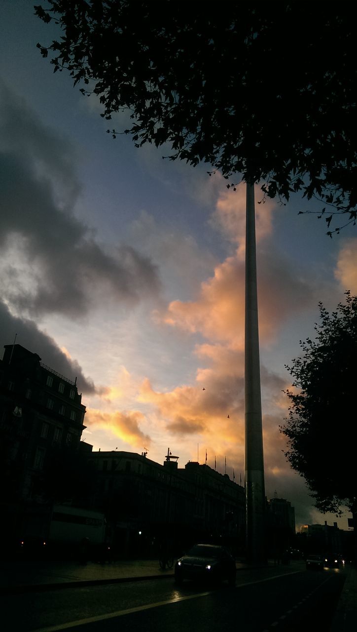 transportation, car, land vehicle, mode of transport, road, sky, street, tree, sunset, architecture, traffic, built structure, city, street light, cloud - sky, on the move, silhouette, building exterior, the way forward, road marking