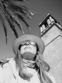 Portrait of young woman standing against sky